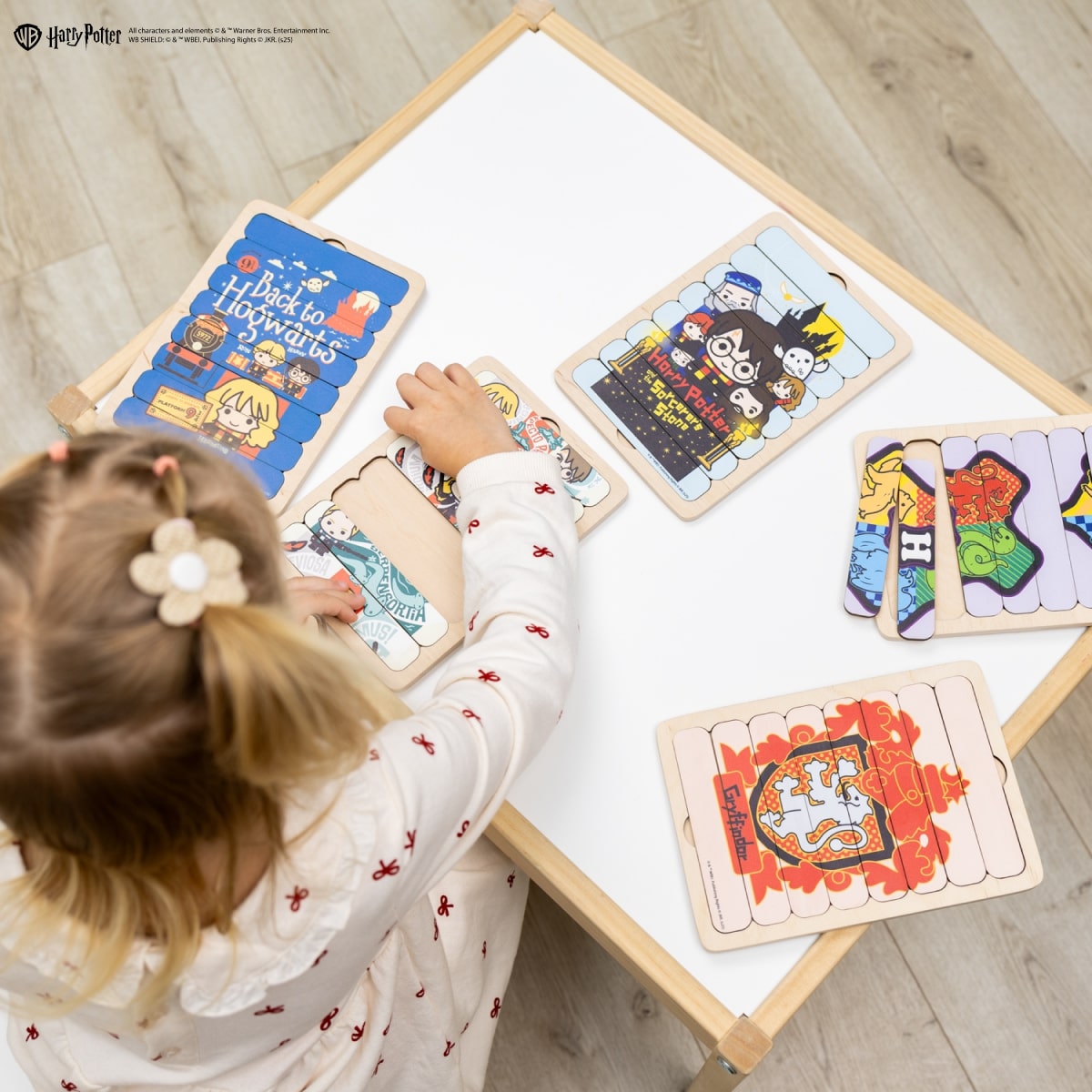 Child playing with Harry Potter-themed wooden puzzles on a table.