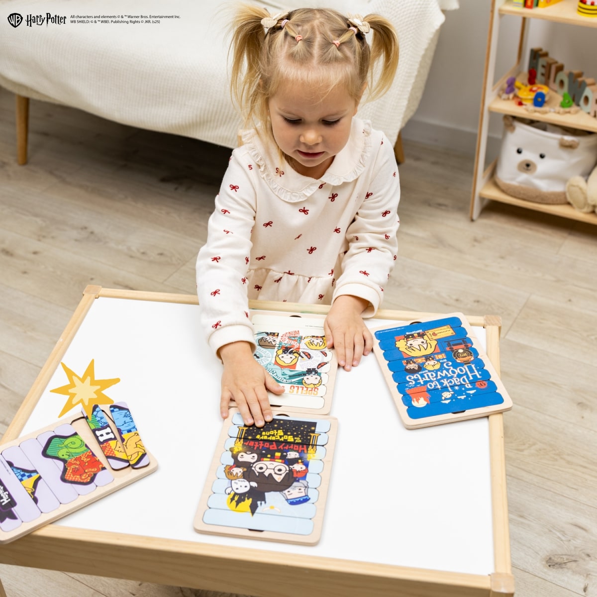 Child playing with educational toys on a wooden table in a room with toys in the background