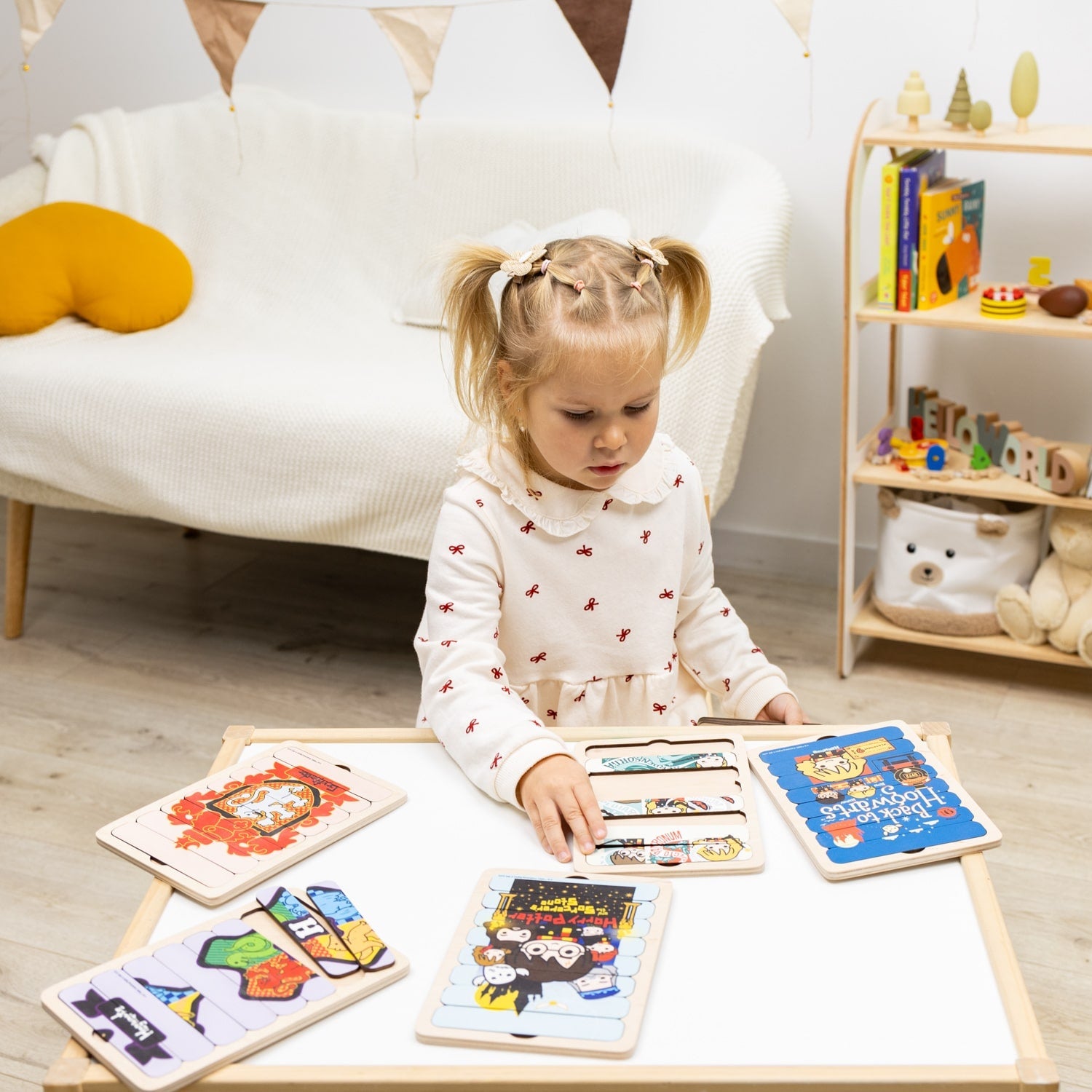Child playing with educational toys on a table in a room with a bookshelf and soft furniture.