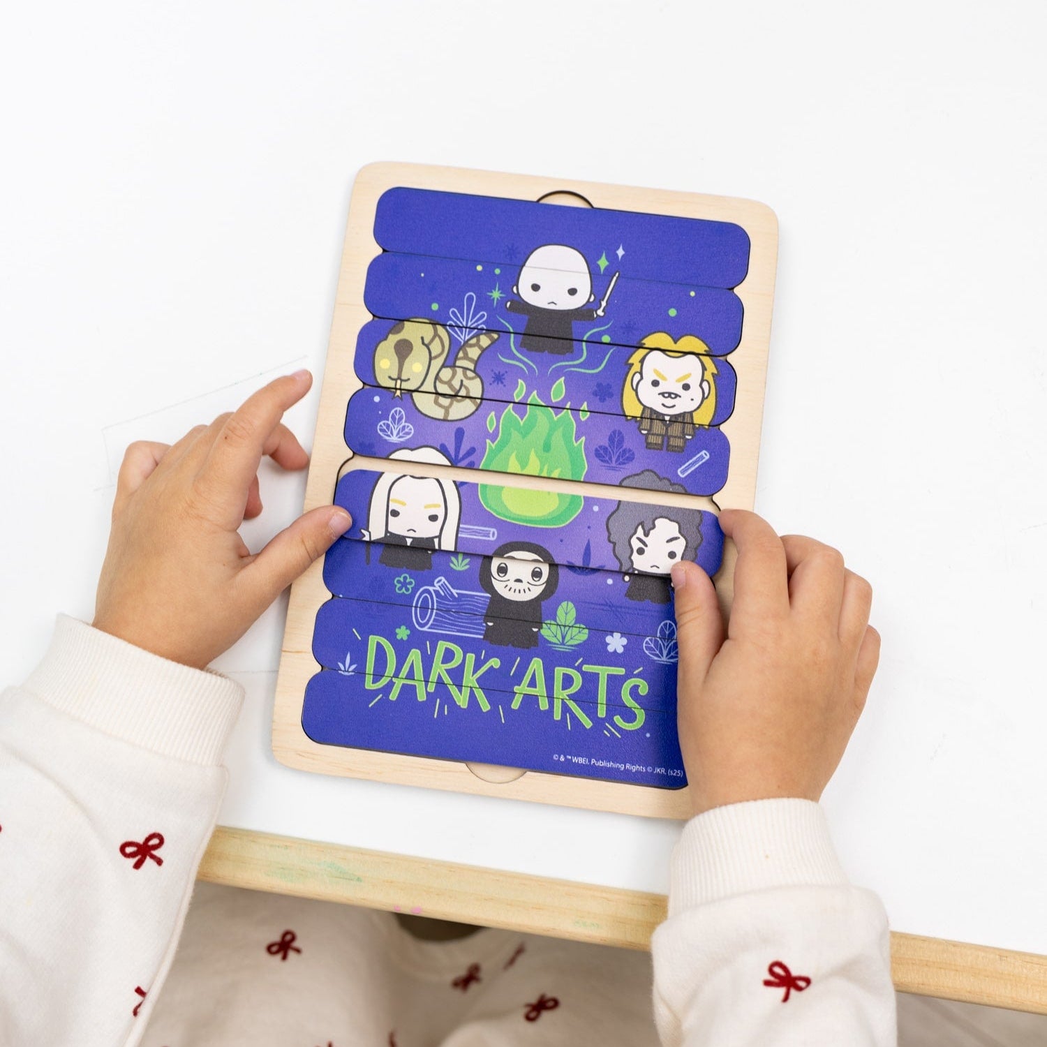 Child holding a wooden puzzle with cartoon characters on a white background