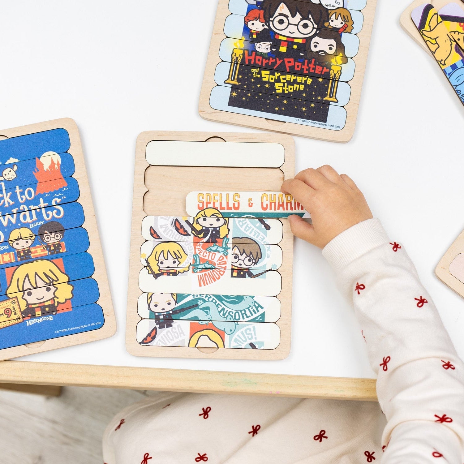 Child playing with a Harry Potter-themed wooden puzzle on a light surface.