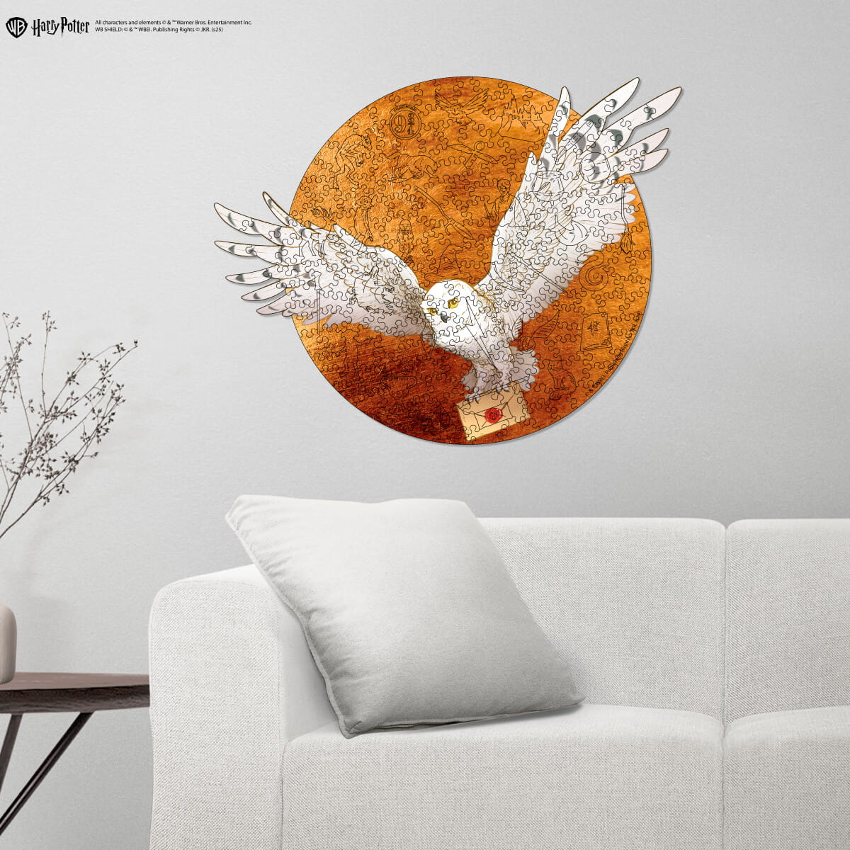 Decorative wall art of an owl with a round brown background on a gray wall above a white sofa.