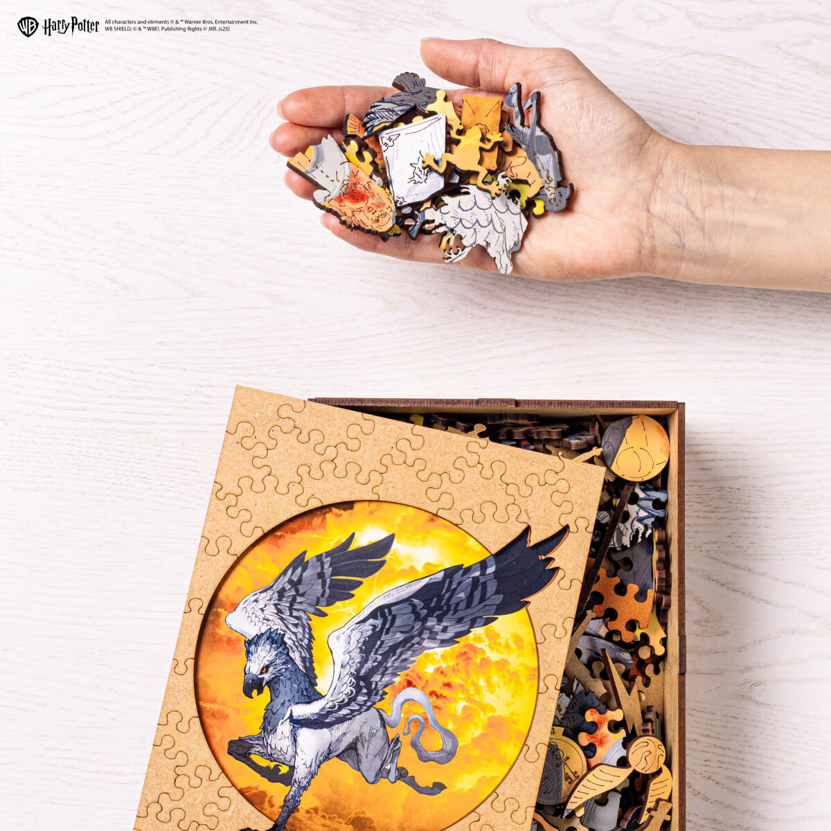 Hand holding a partially completed puzzle with a dragon design, next to an unassembled puzzle box featuring a dragon illustration.