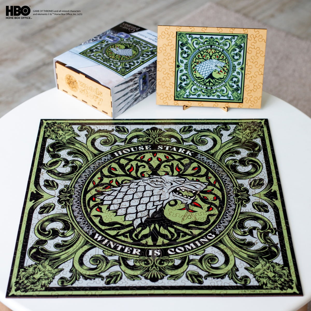 Decorative mat with 'House Stark' design featuring a wolf and 'Winter is Coming' text, surrounded by packaging on a white surface.