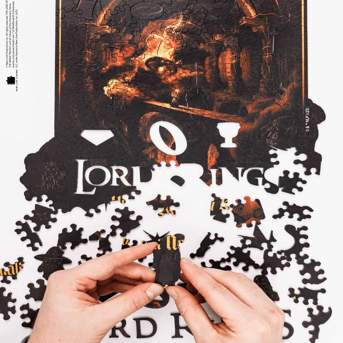 Jigsaw puzzle with 'The Lord of the Rings' branding, partially completed with hands holding a piece.