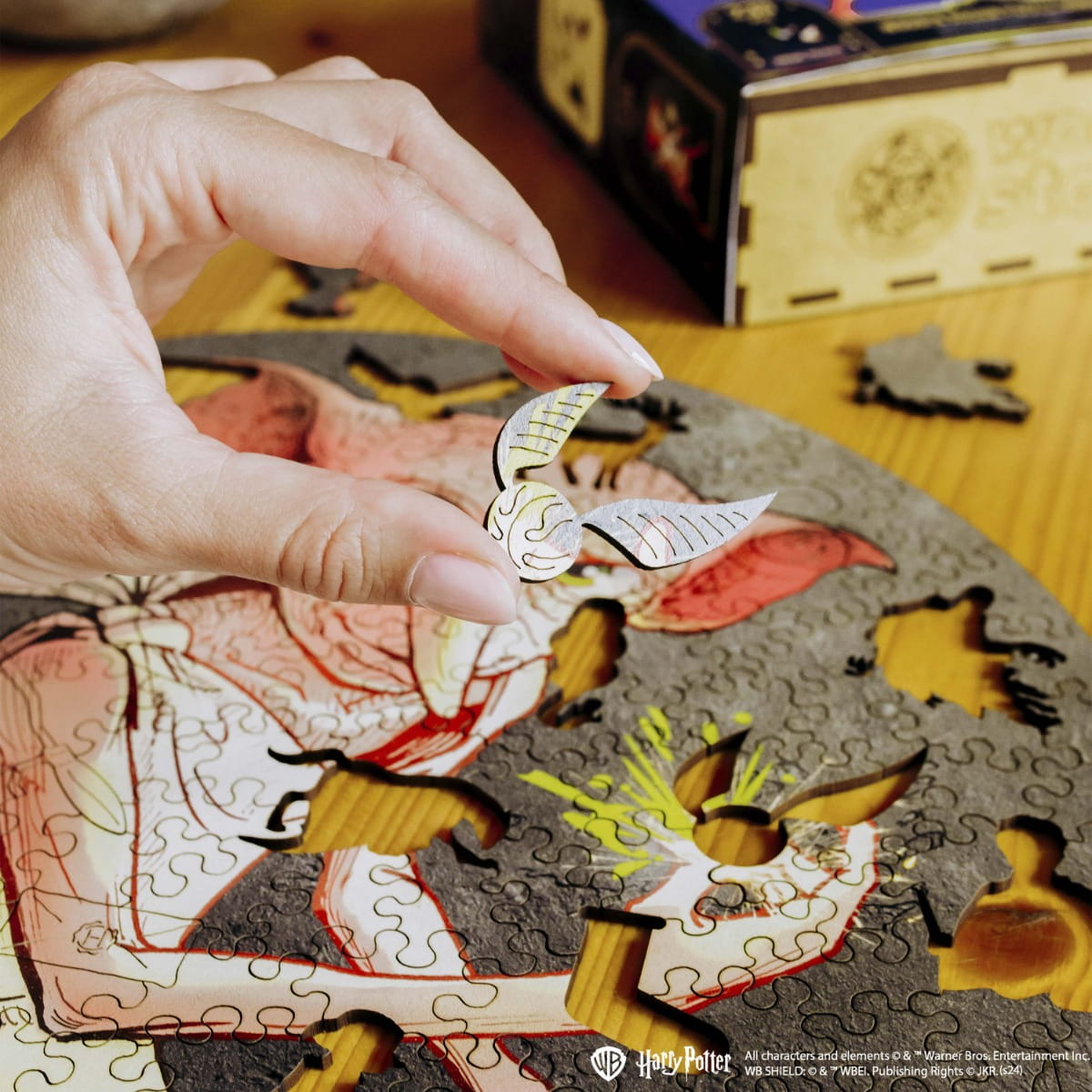 Hand holding a puzzle piece with a character from 'Harry Potter' next to a partially completed puzzle.