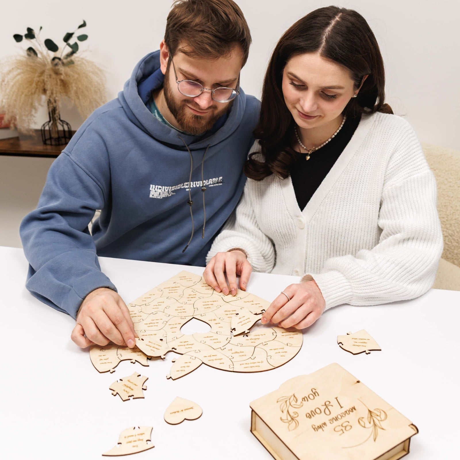 Two people working on a wooden puzzle together.