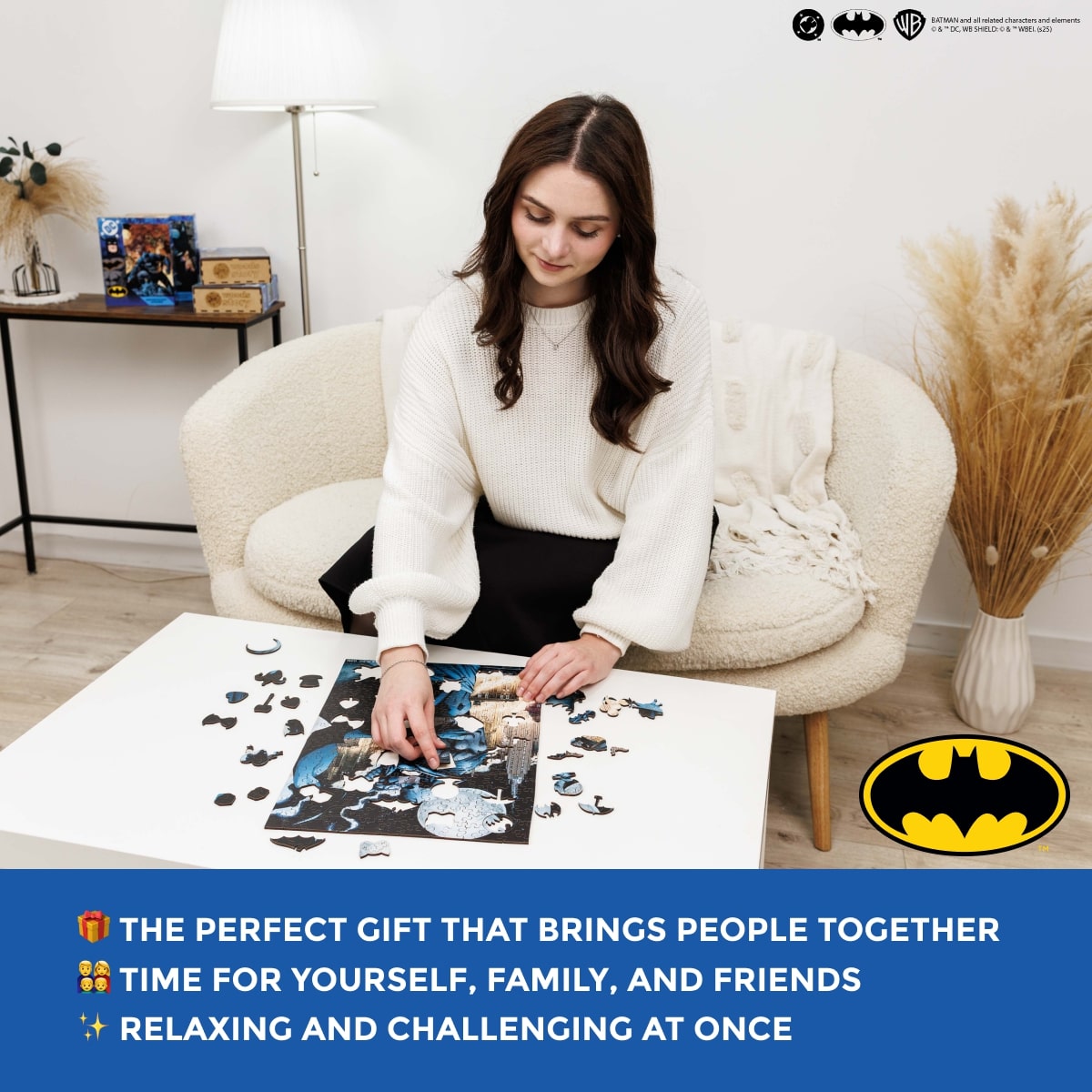 Woman sitting on a chair with a Batman-themed puzzle, surrounded by decorative items.